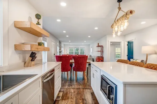 a kitchen with kitchen island a stove a sink a refrigerator and a dining table with wooden floor