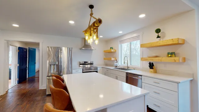 a kitchen with stainless steel appliances a sink a stove a refrigerator cabinets and wooden floor