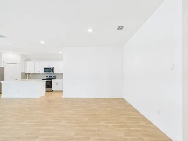 a view of empty room with kitchen and window