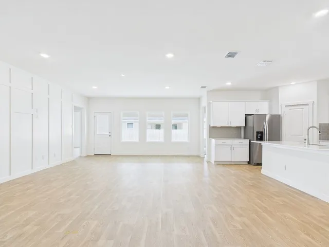 a view of kitchen with stainless steel appliances kitchen island a sink dishwasher a refrigerator and white cabinets with wooden floor