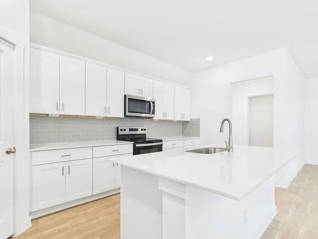 a kitchen with stainless steel appliances granite countertop white cabinets a stove a microwave and a refrigerator