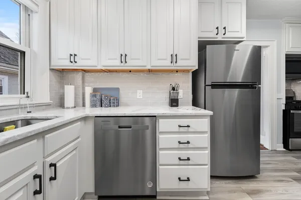 a kitchen with white cabinets and refrigerator