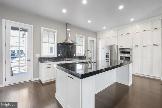a large kitchen with stainless steel appliances kitchen island granite countertop a large counter top and wooden floors