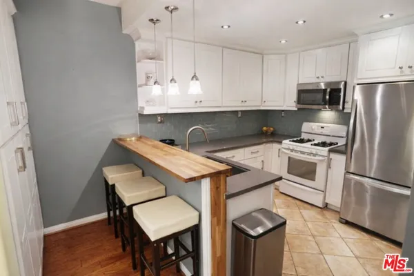 a kitchen with stainless steel appliances granite countertop a white cabinets and wooden floor