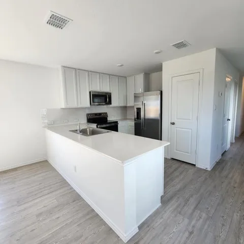 a large kitchen with cabinets and wooden floor