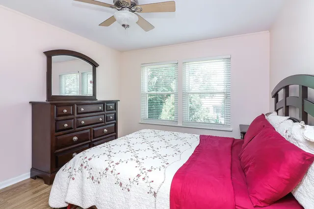 a bedroom with a bed and a dresser with wooden floor