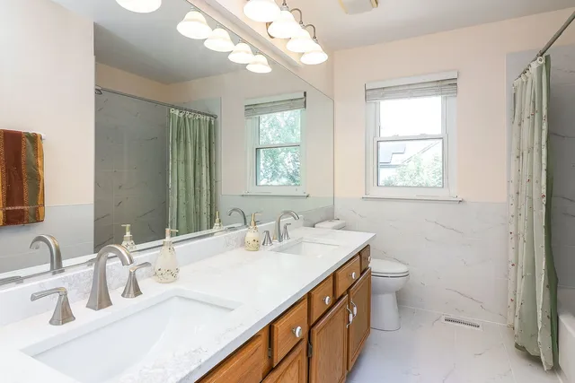 a bathroom with double vanity a toilet a and a window