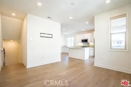 a view of kitchen with kitchen island a sink wooden floor and a refrigerator
