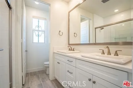 a bathroom with a granite countertop sink a toilet and a mirror