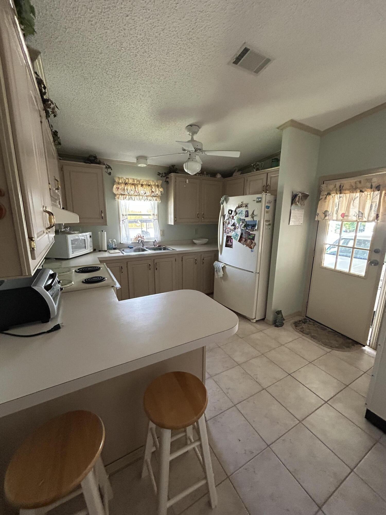 400 North Hwy A1A, Unit 47 Jupiter, FL 33477 - Photo 19 of 35 a kitchen with stainless steel appliances granite countertop a sink a stove a refrigerator a microwave oven with white cabinets and wooden floor