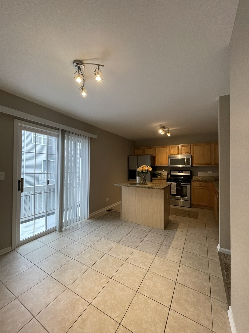 578 Triumph Court, Unit 578 Hainesville, IL 60073 - Photo 7 of 20 a kitchen with stainless steel appliances kitchen island granite countertop a refrigerator and a sink