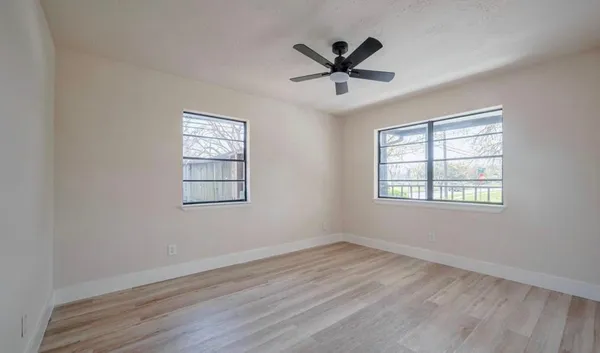 a view of a big room with wooden floor windows and chandelier fan