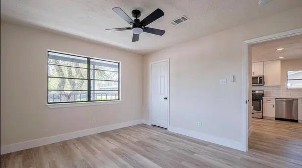 a view of an empty room with wooden floor and a window