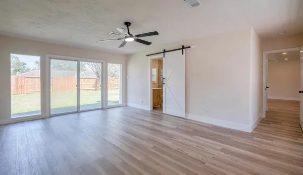 a view of an empty room with wooden floor and a window