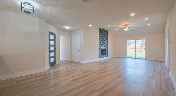 a view of an empty room with wooden floor and windows