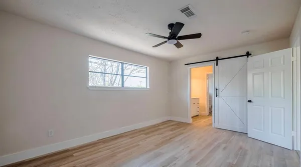 a view of empty room with wooden floor and fan