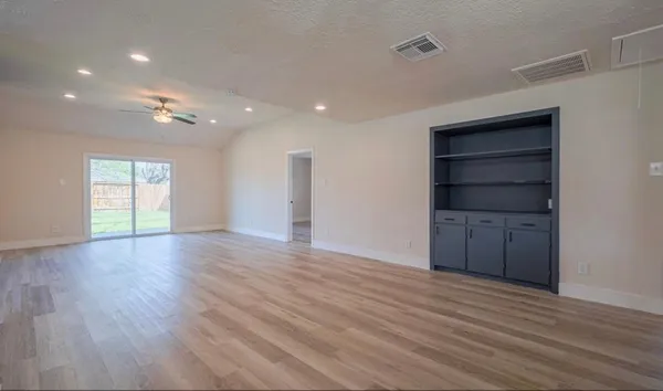a view of an empty room with a window and wooden floor