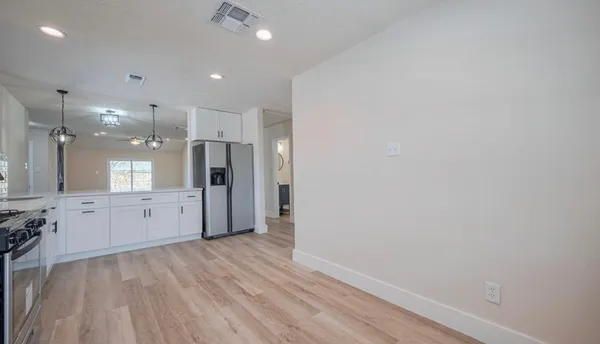 a large white kitchen with a refrigerator a sink dishwasher and a stove with wooden floor