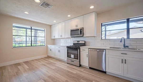 a kitchen with stainless steel appliances granite countertop a stove a sink dishwasher and a microwave oven with wooden floor