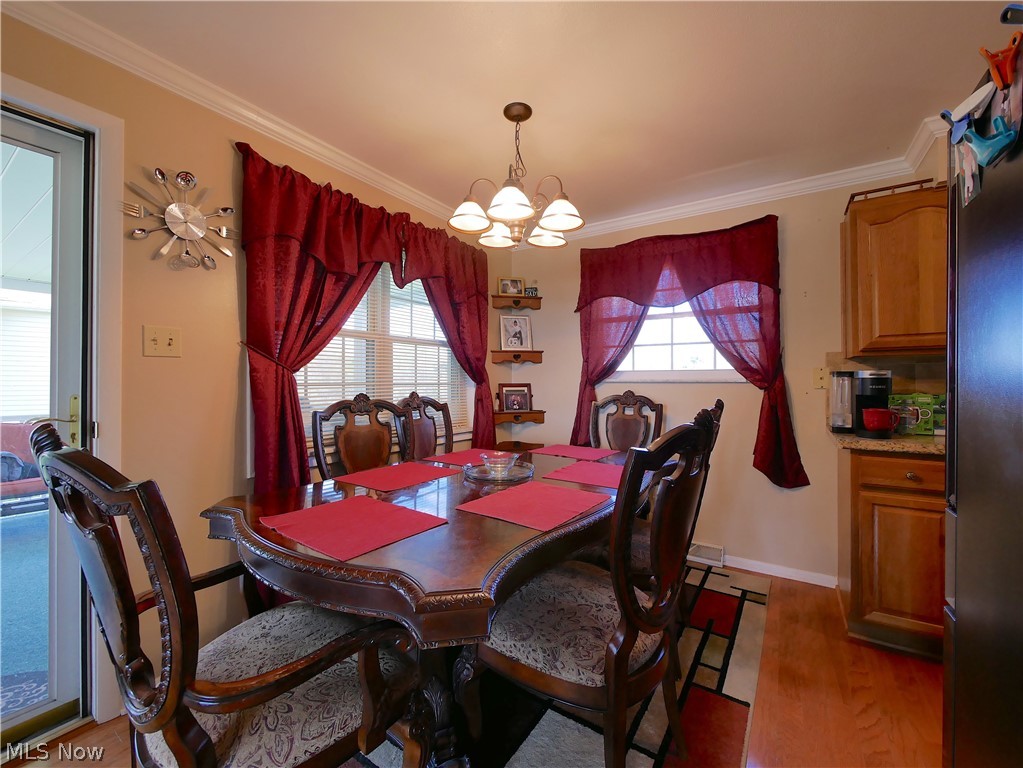 173 Patterson Road Weirton, WV 26062 - Photo 13 of 31 Dining area with light hardwood / wood-style floors, an inviting chandelier, and ornamental molding