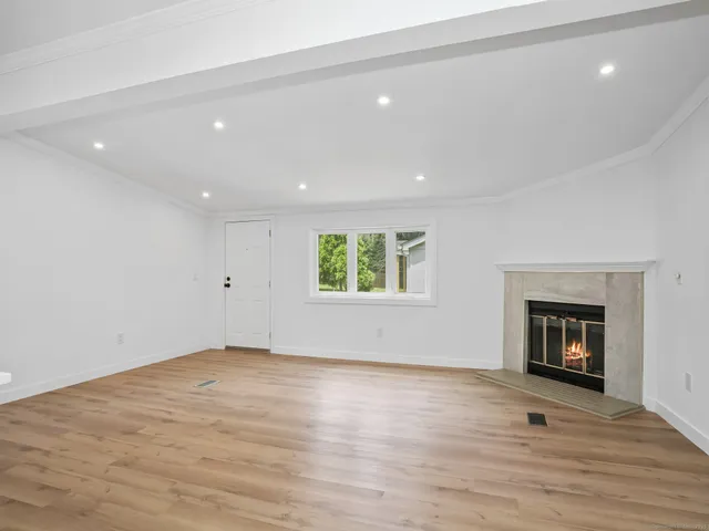 an empty room with wooden floor a fireplace and windows