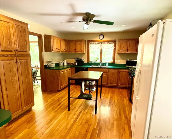 a dining hall with stainless steel appliances granite countertop a refrigerator a stove a sink dishwasher with a dining table and chairs with wooden floor