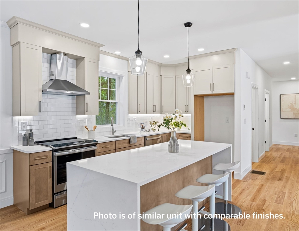 75 Franklin Street, Unit 1 Arlington, MA 02474 - Photo 9 of 36 a kitchen with stainless steel appliances a table chairs and a refrigerator