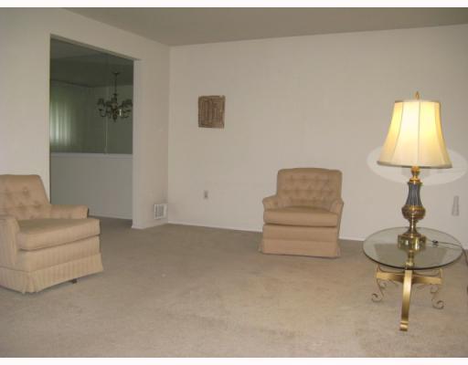 Living Room. Living room with beige carpeting, white walls, sheer draperies on large window, newer front door.