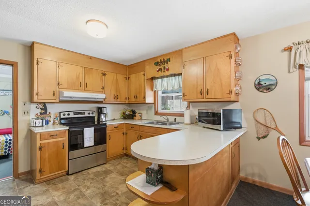a kitchen with stainless steel appliances granite countertop a stove top oven a sink dishwasher and cabinets with wooden floor