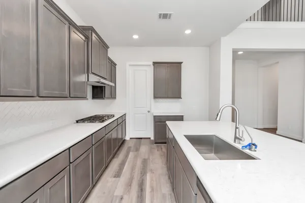 a large white kitchen with a stove top oven a sink dishwasher and a refrigerator with wooden floor