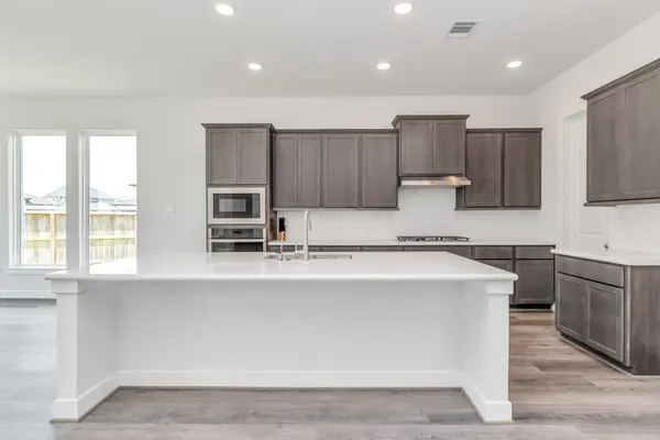 a large kitchen with stainless steel appliances a large counter top and a stove top oven