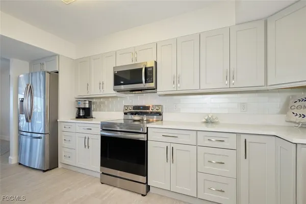 a kitchen with white cabinets and stainless steel appliances