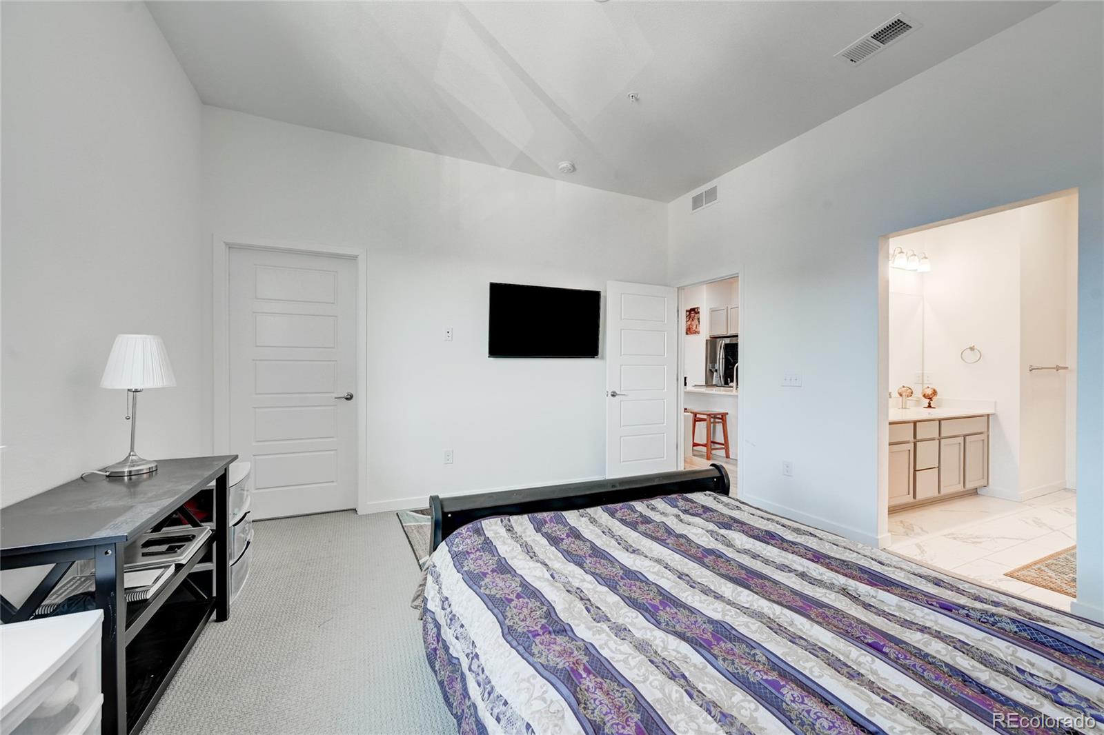 9287 Twenty Mile Road, Unit 405 Parker, CO 80134 - Photo 15 of 28 a bedroom with a bed and a flat screen tv