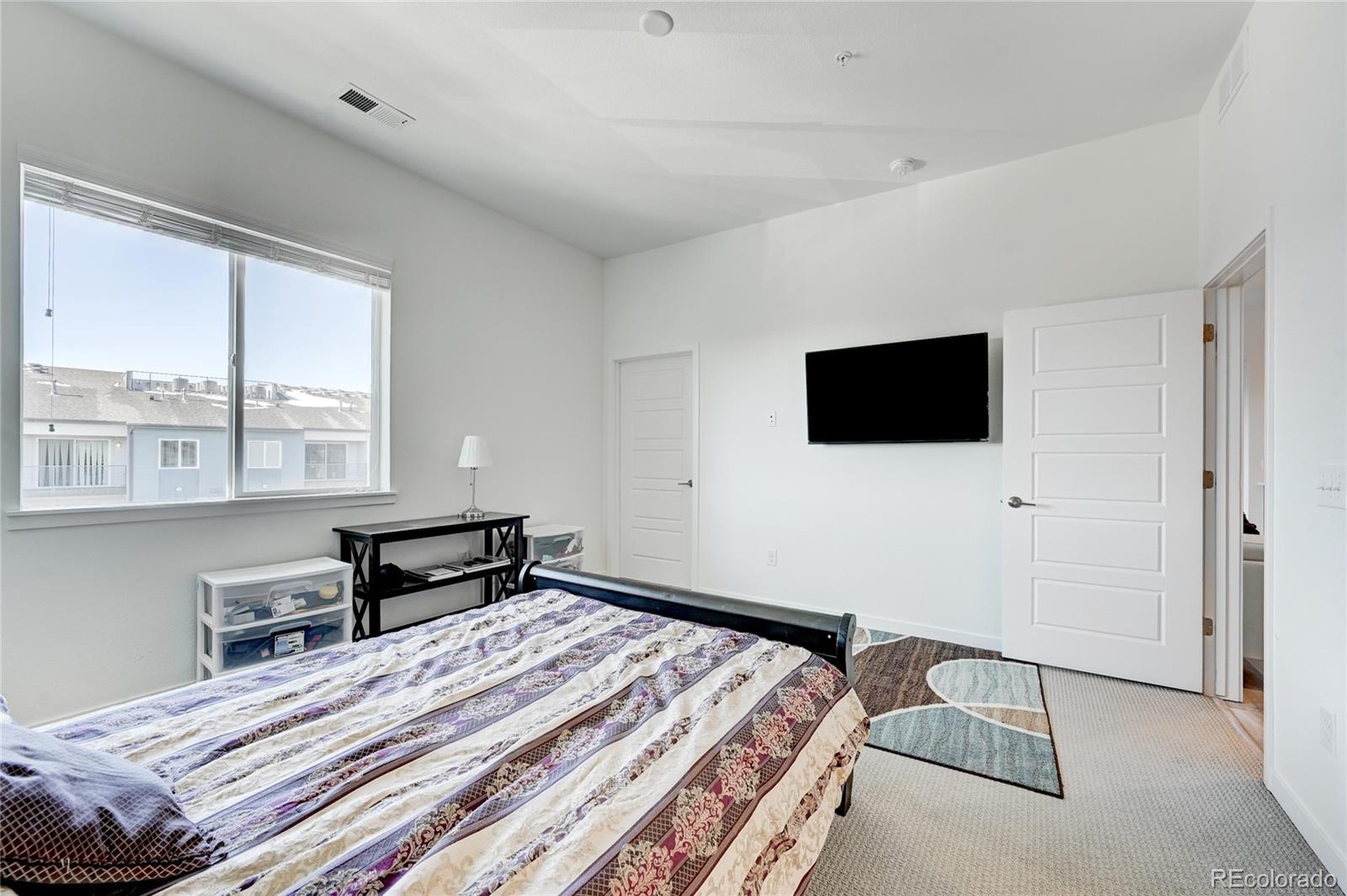 9287 Twenty Mile Road, Unit 405 Parker, CO 80134 - Photo 16 of 28 a bedroom with a bed and a flat screen tv