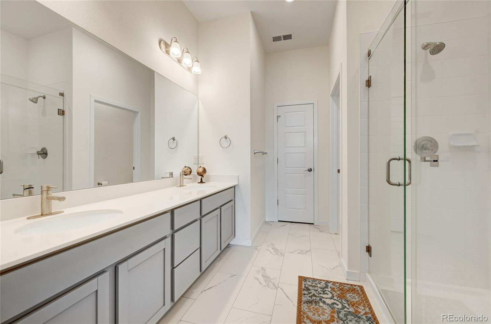 9287 Twenty Mile Road, Unit 405 Parker, CO 80134 - Photo 17 of 28 a spacious bathroom with a double vanity sink mirror and shower