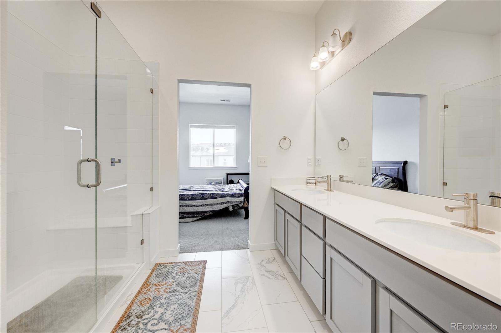 9287 Twenty Mile Road, Unit 405 Parker, CO 80134 - Photo 18 of 28 a spacious bathroom with a double vanity sink a mirror and a shower