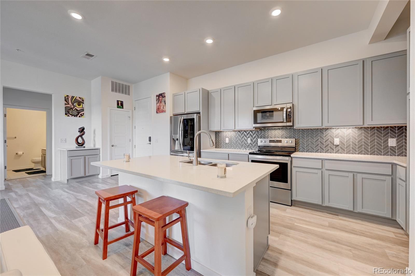 9287 Twenty Mile Road, Unit 405 Parker, CO 80134 - Photo 2 of 28 a kitchen with stainless steel appliances granite countertop a stove top oven a sink a refrigerator and white cabinets with wooden floor