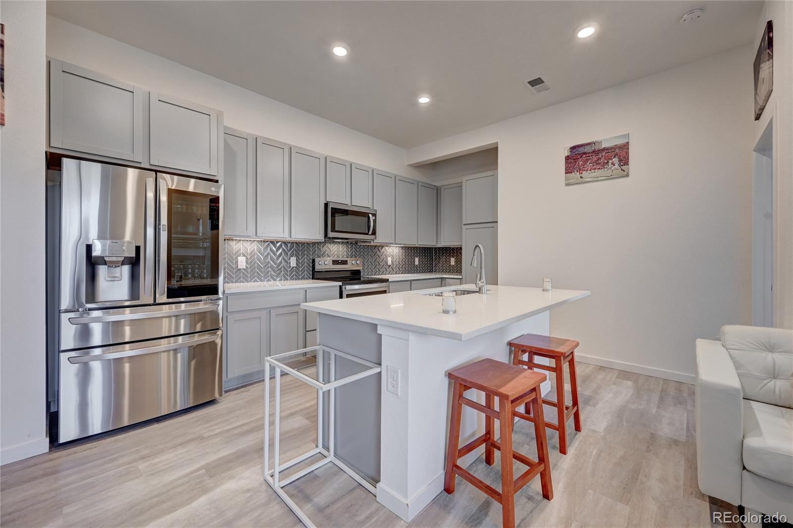 9287 Twenty Mile Road, Unit 405 Parker, CO 80134 - Photo 10 of 28 a kitchen with kitchen island granite countertop stainless steel appliances cabinets a sink and a refrigerator