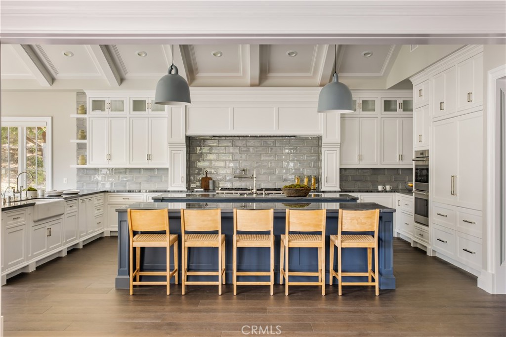 24200 Hidden Ridge Road Hidden Hills, CA 91302 - Photo 12 of 61 a kitchen with white cabinets and chairs