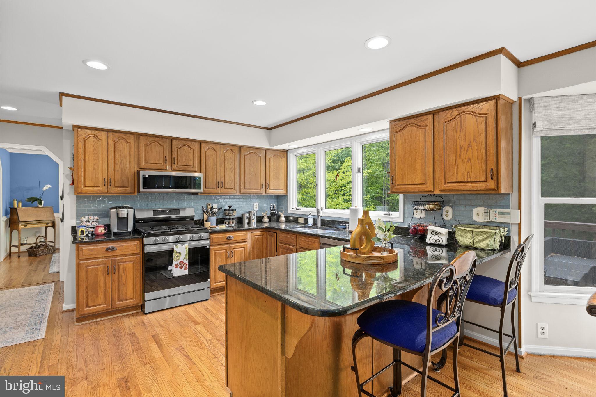 100 Boscobel Road Fredericksburg, VA 22405 - Photo 25 of 67 a kitchen with stainless steel appliances granite countertop a stove top oven a sink dishwasher a dining table and chairs with wooden floor