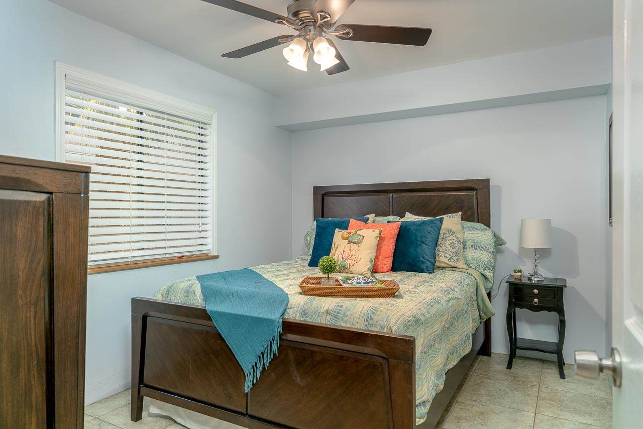 2219 South Kihei Road, Unit B216 Kihei, HI 96753 - Photo 15 of 29 a bed sitting in a bedroom next to a window with a chandelier and a chair