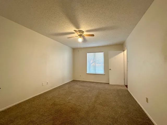 an empty room with windows and fan