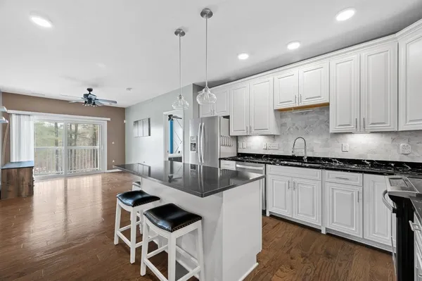 a kitchen with granite countertop stainless steel appliances a refrigerator a stove top oven and cabinets