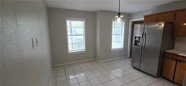 a view of an empty room with window and refrigerator