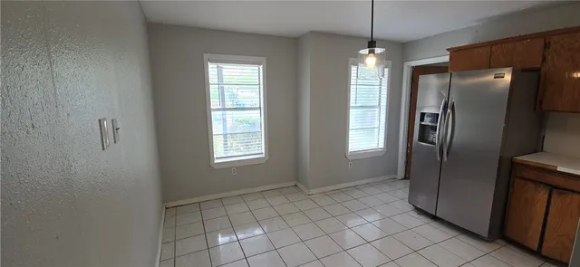 a view of an empty room with window and refrigerator