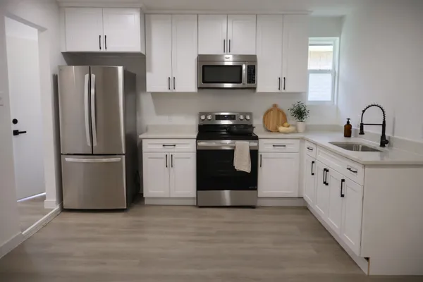 a kitchen with stainless steel appliances granite countertop a refrigerator stove a sink and dishwasher with wooden floor