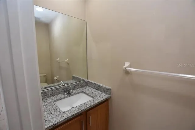 a bathroom with a granite countertop sink and a mirror