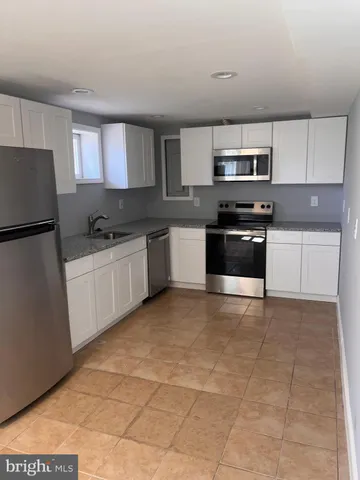 a kitchen with stainless steel appliances a sink a stove a microwave a sink a refrigerator and cabinets