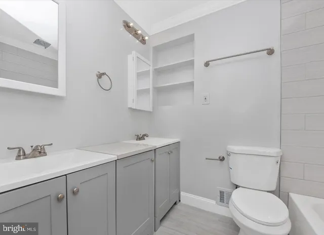 a bathroom with a toilet sink vanity and mirror