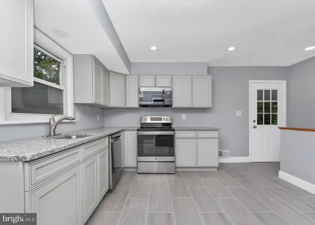 a kitchen with granite countertop white cabinets stainless steel appliances and a sink
